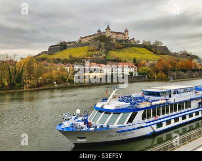 Blick auf die Festung Marienberg, umgeben von Weinbergen und dem Main mit einem Boot in Würzburg, Deutschland. Stockfoto