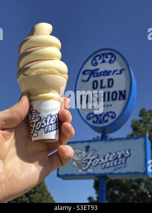 Burbank, CA / USA - 28. März 2021: Vor einem Fosters Freeze-Schild hält eine Hand einen Schoko- und Vanilleeiskegel. Diese kalifornische Restaurantkette wurde 1946 gegründet. Stockfoto