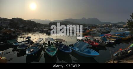 Die Boote parkten in der Taifun-Schutzhütte Sai Kung, wobei die Sonne hinter Ma auf der Shan Range unterging. Stockfoto