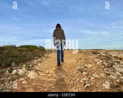 Rückansicht einer Frau in legerer Kleidung, die entlang geht Ein abgelegener Fußweg Stockfoto