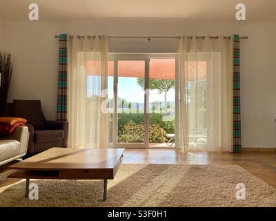 Modernes Wohnzimmer mit Sonneneinstrahlung durch Glasschiebetüren Türen Stockfoto