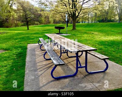 Ein leerer Picknickplatz in einem schönen Park mit einem Grill, einem Picknicktisch und einer langen, angeschlossenen Bank, Ontario, Kanada. Covid-Beschränkungen für Versammlungen halten Menschen fern, hoffentlich nicht lange. Stockfoto