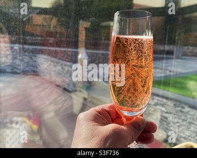 Flötenglas Rosenchampagner hoch gehalten Stockfoto