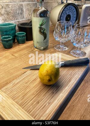 Zitrone bereit für das Schneiden in nicht-alkoholische gegeben werden gin und Tonic (Gin & Tonic) Mit einer Seedlip-Flasche und einer Brille im Hintergrund Eine Küche Stockfoto