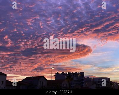 Rote Sonnenuntergangswolken über der Skyline der Stadt in Palavas les Flots in der Nähe von Carnon Plage und Montpellier, im Süden Frankreichs, in der Region von okzitanien Stockfoto