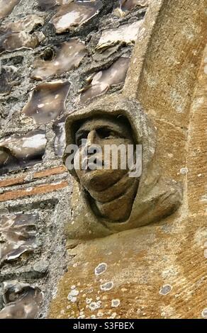 Geschnitzter religiöser Kopf aus Stein auf dem Türrahmen der Sakristei der Church of St Mary in Longstock, Hampshire Stockfoto