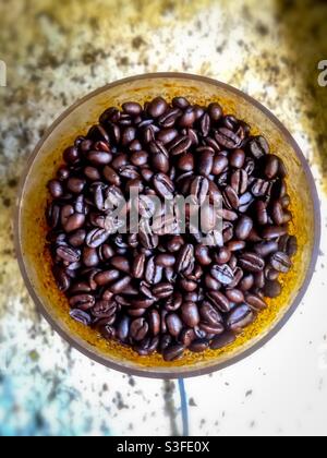 Frisch geröstete Arabica-Kaffeebohnen in einer runden Schüssel auf einer Granittheke. Hauptsächlich von Entwicklungsländern angebaut und exportiert, wird es vor allem in entwickelten Ländern konsumiert. Stockfoto