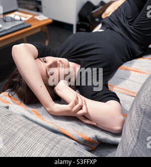 Nachdenkliche junge Frauen liegen auf der Couch Stockfoto
