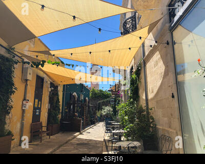 Ansicht der Straßencafé-Stühle in einer engen Straße in der Altstadt von Limassol, Zypern im Mai 2021. Am Ende der Straße befindet sich die Kebir Moschee. Stockfoto