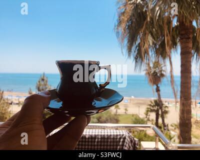 Frischer türkischer Kaffee, serviert in einer authentischen Kaffeetasse vor einem wunderschönen Blick aufs Meer Stockfoto