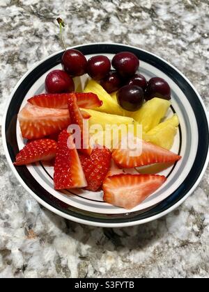 Erdbeeren, Ananas und Kirschen in einer Schüssel. Stockfoto