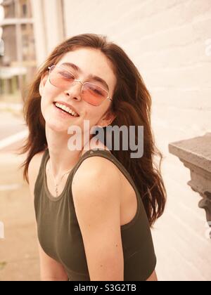 Portrait, hübsche junge Frau lächelnd, Brünette mit langen Haaren und Sonnenbrille Stockfoto