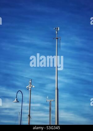 Wetterstation, Überwachungskameras und Deckenbeleuchtung vor blauem Himmel und streifigen Wolken Stockfoto