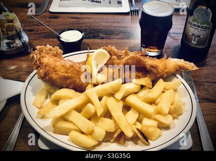 Authentischer Fisch und Chips mit einem Pint schwarzem Bier in Whitby, Yorkshire, großbritannien Stockfoto