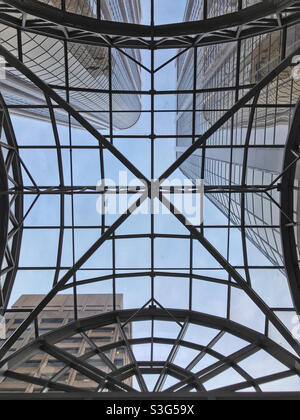 Blick nach oben durch eine gemusterte Glasdecke auf die hoch aufragenden Bürogebäude darüber. Downtown Calgary, Alberta, Kanada. Stockfoto