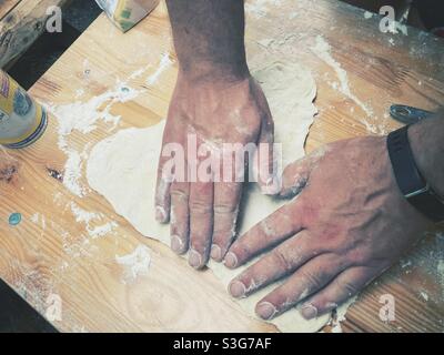 A man‘Hand eine Pizza aus frischem Teig Formen Stockfoto