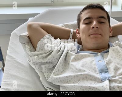 Porträt eines Patienten in einem Krankenhauskleid in der Operationsklinik, die auf eine Operation wartet. Er ruht sich auf dem Krankenhausbett aus. Stockfoto