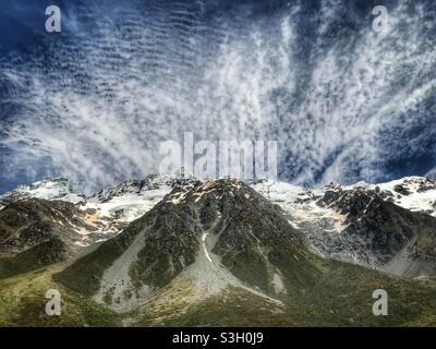 Vom Hooker Valley Track, South Island, Neuseeland aus gesehen, strömen Wolken über einen verschneiten Gipfel im Aoraki Mount Cook National Park Stockfoto