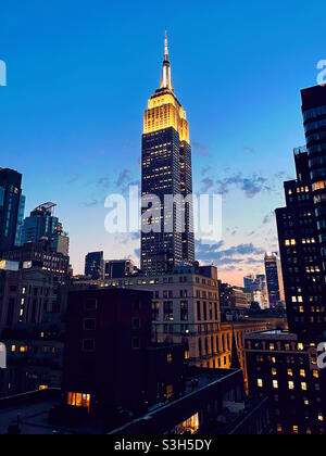 Das Empire State Building leuchtet in der frühen Abenddämmerung in Midtown Manhattan, NYC, USA Stockfoto