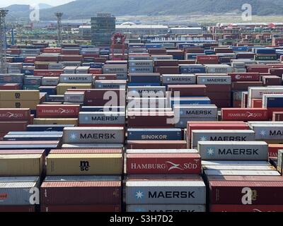 Blick von der Navigationsbrücke des Frachtschiffes auf die Container verschiedener Spediteure, die im Terminal im Hafen von Kwangyang in Südkorea verstaut wurden. Stockfoto