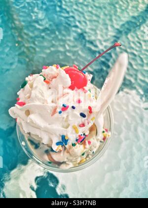 Eisbecher mit Schlagsahne-farbigen Streuseln und einer Kirsche auf der Oberseite von oben gesehen. Sommertag Spaß behandeln Urlaub Konzept. Stockfoto