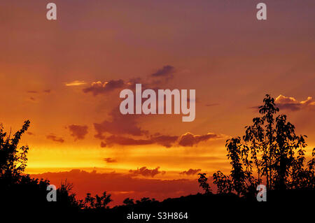 Blick auf den Sonnenuntergang und die Sonnenstrahlen in den Wolken Stockfoto
