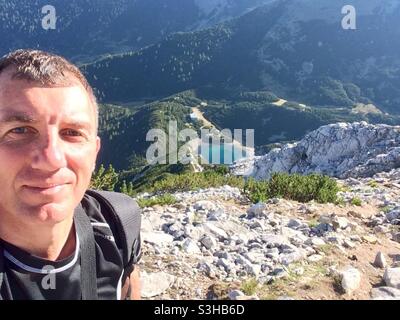 Wandern in Bulgarien. Männlicher Wanderer, der ein Selfie-Foto auf dem Sinanitsa-Gipfel mit Blick auf den Sinanitsa-Gletschersee und die Hütte im Pirin-Gebirge, Bulgarien, Balkan, Europa, macht. Stockfoto