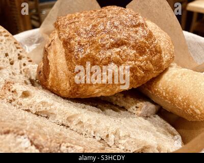 Pain au Chocolate in einem Korb mit frisch gebackenen Brotscheiben, die für einen kontinentalen Frühstücksbrunch serviert werden. Stockfoto