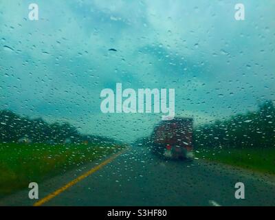 Ein LKW, der bei starkem Regen auf der Autobahn, Québec, Kanada, fährt. Regentropfen reduzieren die Sicht und schaffen herausfordernde Bedingungen für alle Fahrer. Schlechtes Wetter. Stockfoto