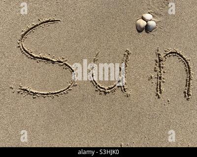 Schreiben am Strand in nassem Sand: Sonne, es gibt ein paar Muscheln um ihn herum Stockfoto