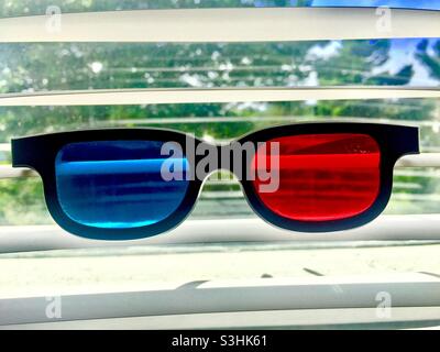 3D-Brille an einem Fenster vor venezianischen Jalousien, Kanada. Rosa und Blau, ein surrealer Blick. RGB. R und B in der Brille, G draußen. Stockfoto