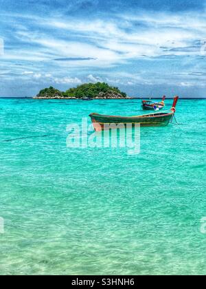 Vertikale Ansicht von Langschwanz-Booten, die in klarem Wasser auf Koh Lipe, Südthailand, verankert sind Stockfoto