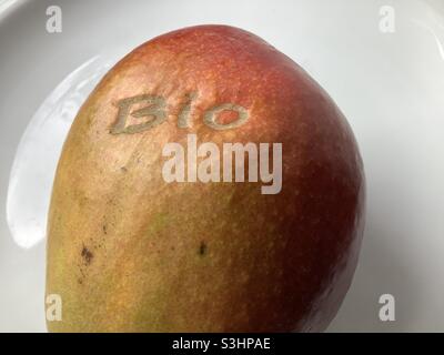 Reife Mangofrucht mit „Bio“-Aufdruck auf Schale isoliert auf weißem Hintergrund Stockfoto