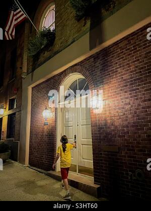 Ein kleines Mädchen läuft vor einer gut beleuchteten Stadthaus-Tür im Murray Hill-Viertel, NYC, USA, 2021 Stockfoto
