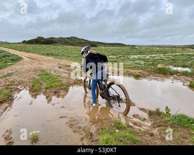 Mädchen steckte im Schlamm, während sie mit dem Mountainbike auf einem Feldweg unterwegs war Stockfoto