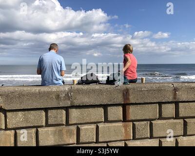 Pärchen, die eine Kaffeepause am Meer machen Stockfoto