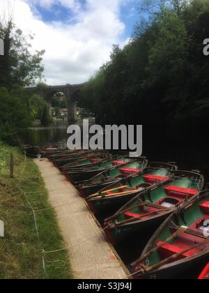 Ruderboote vertäuten vor dem Eisenbahnviadukt über den Fluss Nidd in Knaresborough, North Yorkshire, Großbritannien. Stockfoto