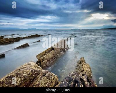 Felsen, die an der Südwestküste Irlands in Ballinskelligs Bay, Grafschaft Kerry, im August ins Meer gelangen. Stockfoto