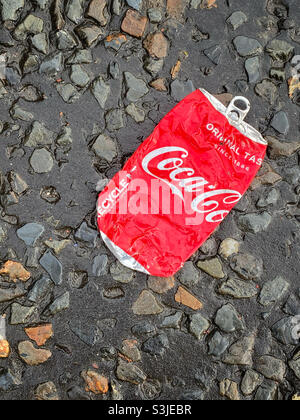 Eine zerquetschte Dose von Original Taste Coca-Cola wurde auf eine Straße geworfen. Dieses Getränk ist sehr hoch in Zucker und Kalorien. Ist es Müll?! Foto ©️ COLIN HOSKINS. Stockfoto