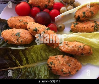 Türkisches Vegangericht Rote Linsenbällchen serviert mit Salat und Kirschtomaten und Oliven Stockfoto