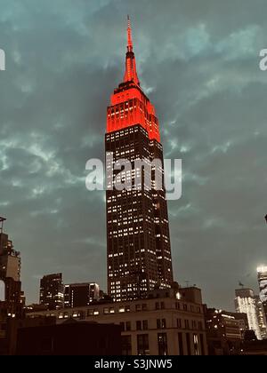 Leuchtend rote Lichter an einem bewölkten, regnerischen Abend über dem Empire State Building Stockfoto