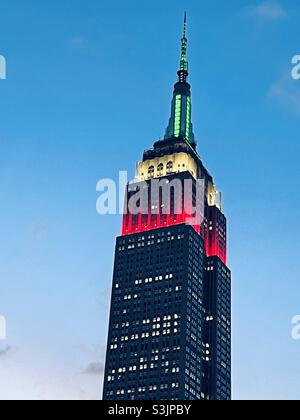Die Turmlichter auf dem Empire State Building Glow rot-weiß und grün vor einem blauen Himmel zu Ehren des italienischen Erbes, NYC, USA Stockfoto