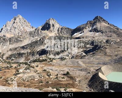 Blick auf den Grand Teton, den Middle Teton und den South Teton, der von der Spitze des Hurrikan-Passes nach Osten blickt. Proglazialsee unter dem Schulraumgletscher im Blick. Stockfoto