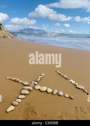 Steine, die Xi am Strand in kefalonia schreiben Stockfoto