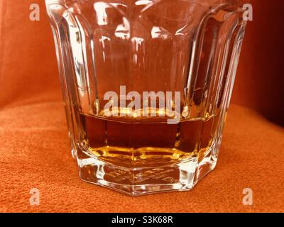 Nahaufnahme eines Glases Whisky auf einer leuchtend orangefarbenen Oberfläche Stockfoto