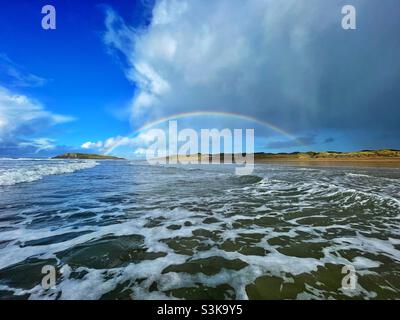 Regenbogen über Llangennith Beach und Burry Holms, Gower, Swansea, South West Wales, Oktober. Stockfoto