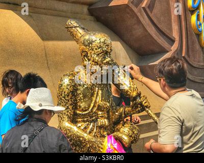 Anhänger legen Blattgold auf eine Statue von Luang Phor Thuad im Wat Huay Mongkol in Hua hin, Thailand Stockfoto