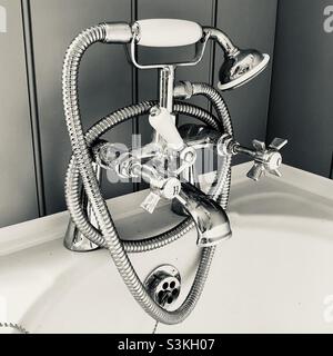 Armaturen im Vintage-Stil und Dusche mit Wandvertäfelung dahinter Stockfoto