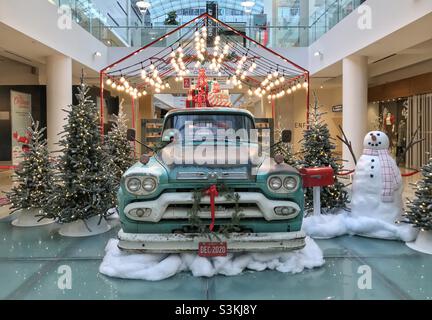 Weihnachtsschmuck in Einkaufszentren im Zentrum von Calgary, Alberta, Kanada, im Dezember 2020. Ein alter Pickup-Truck mit Geschenken, Weihnachtsbäumen, Lichtern, Briefkasten und Schneemann. Stockfoto