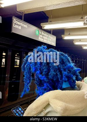 Eine Person mit blauer Afro-Frisur wartet in New York City auf die U-Bahn Stockfoto